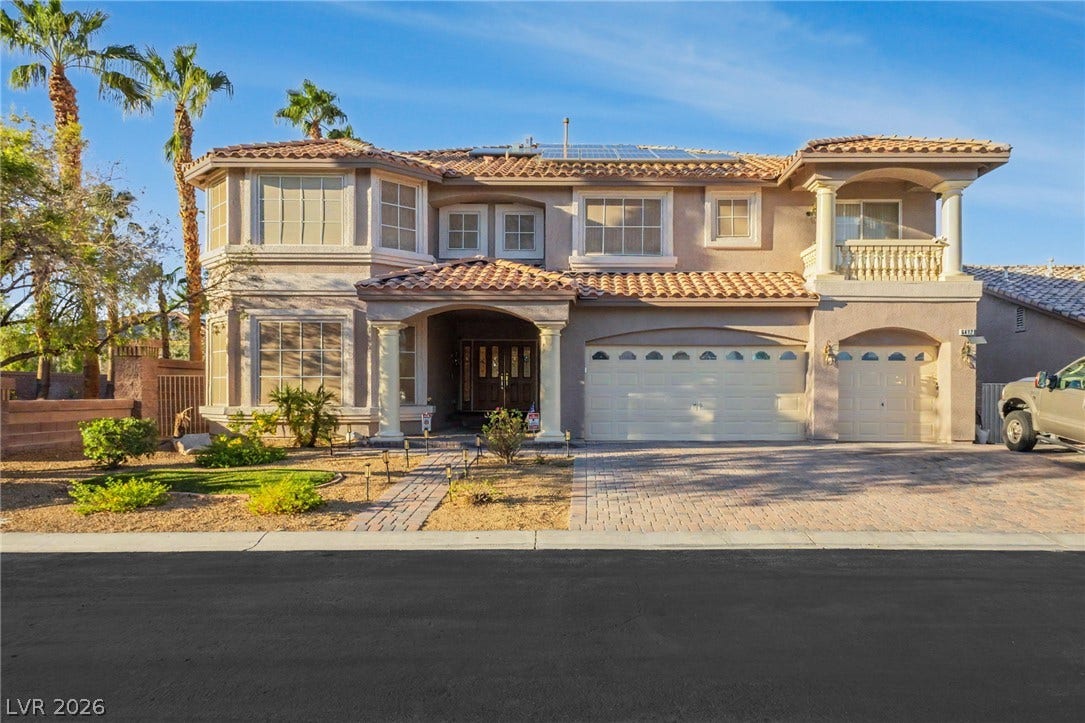 A grand multi-level exterior displays classic Mediterranean roof tiles and an expansive paver driveway.