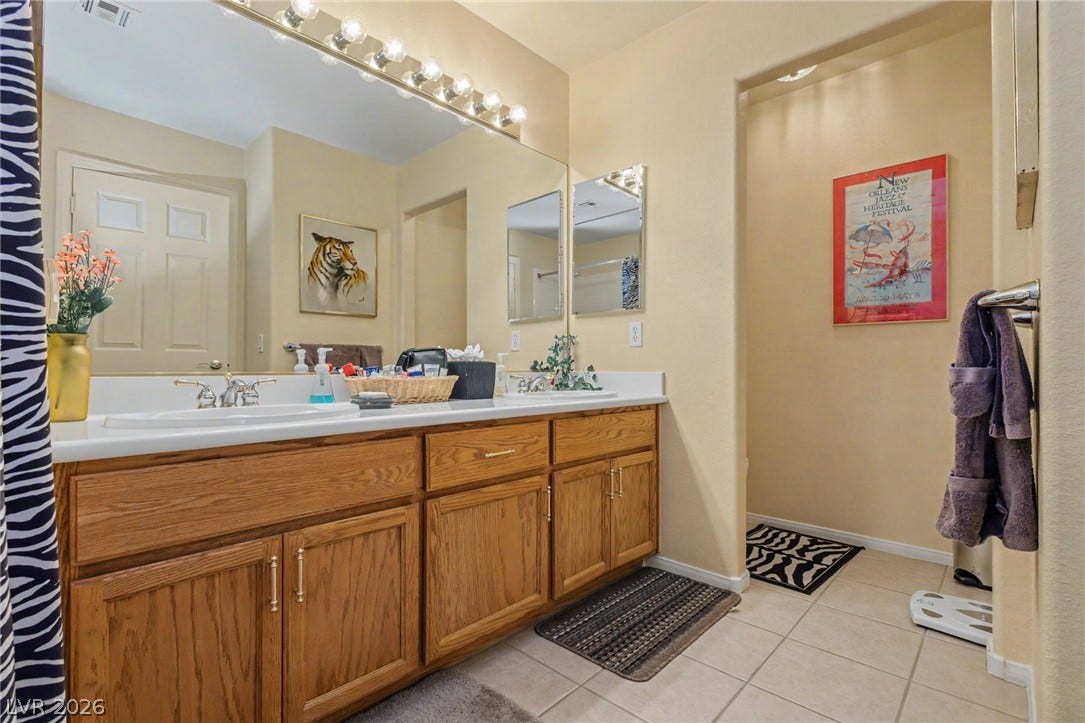 Ample wooden cabinetry and tile flooring define this functional bathroom space.