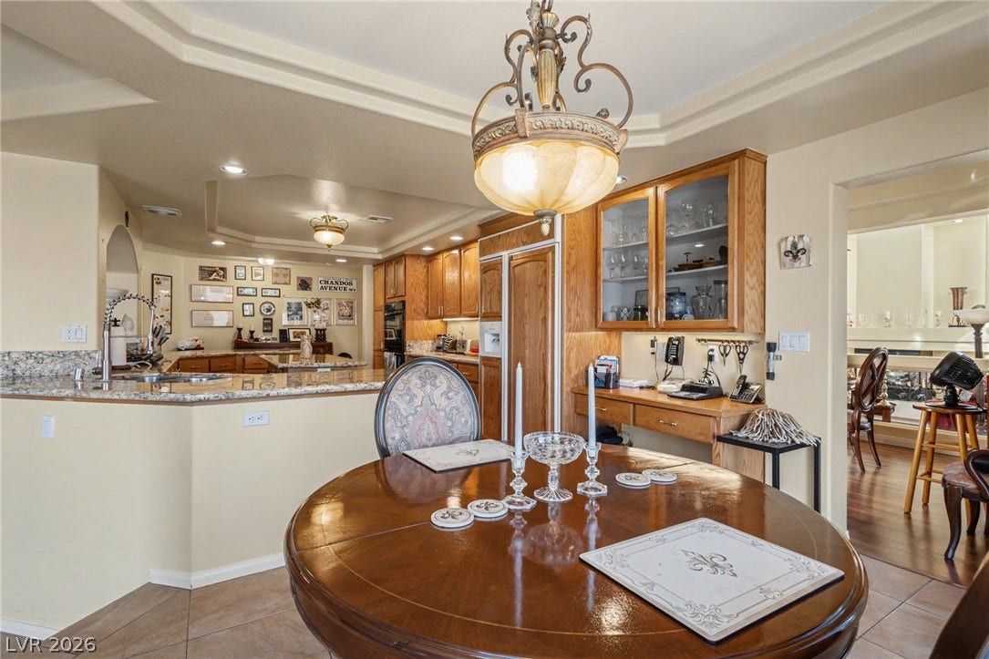 An open dining area flows into the kitchen under a tray ceiling with recessed lighting.