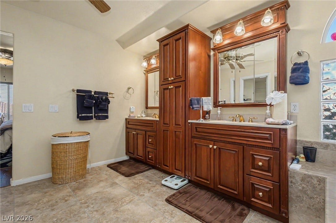Rich wood cabinetry and warm tile floors create a welcoming and timeless primary bath.