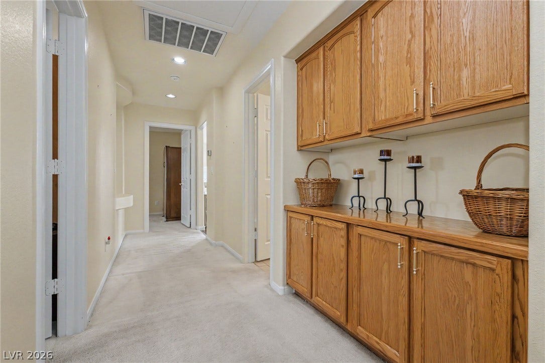 Generous built-in cabinetry provides abundant storage space along this functional hallway.