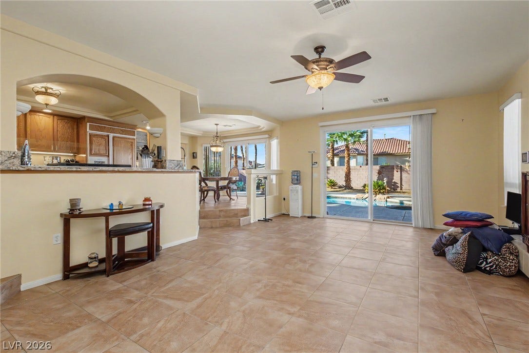 Tiled flooring and sliding doors lead to the backyard pool area from this open living space.