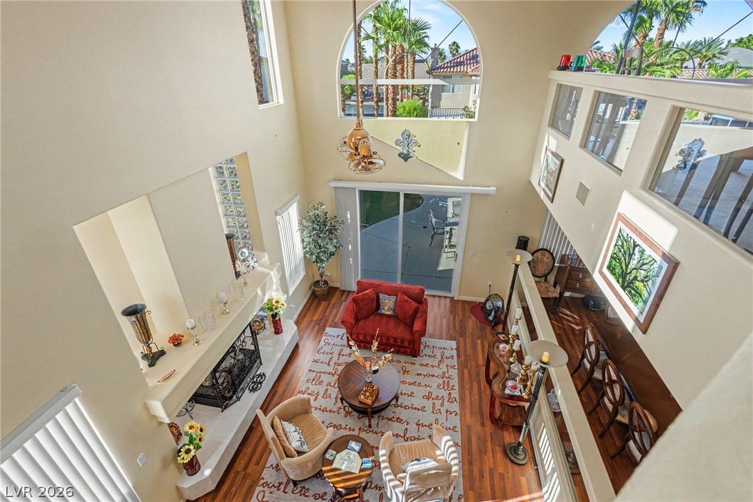 Dramatic high ceilings and a central fireplace anchor this open-concept living space.