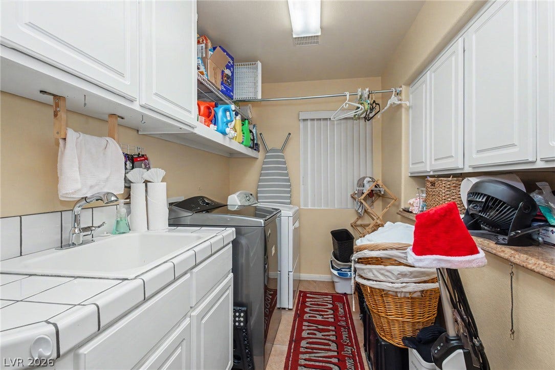 A functional workspace includes built-in cabinetry and a utility sink surrounded by tile countertops.