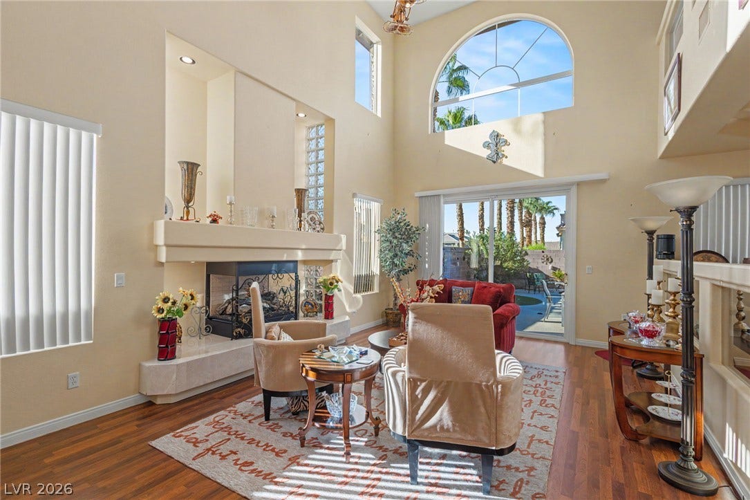 Towering ceilings and a classic fireplace anchor this open living area featuring sliding glass doors.