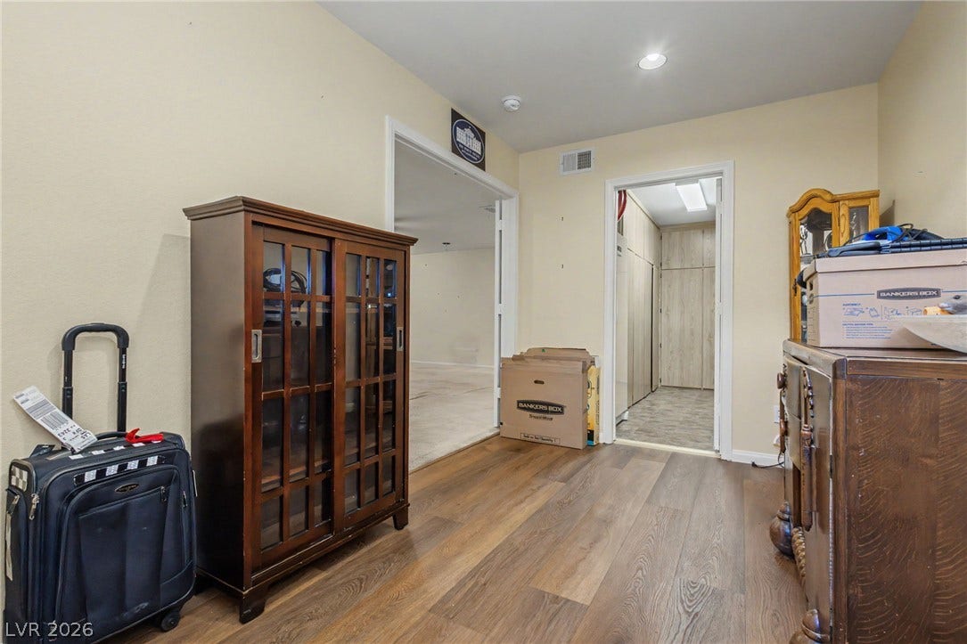 Smooth wood-style flooring runs through this versatile hallway space highlighted by recessed lighting.