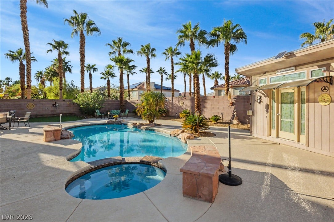Towering palm trees frame an inviting in-ground pool and integrated spa in the backyard.
