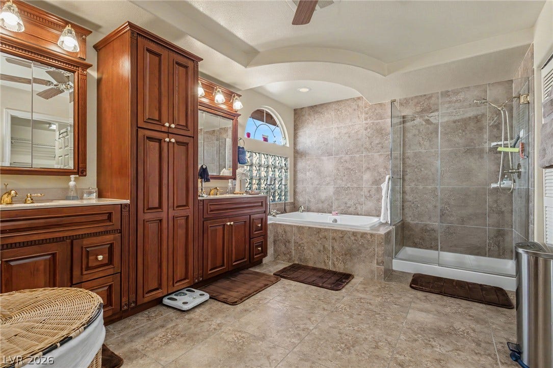 Rich wood cabinetry contrasts beautifully with tiled walls and a glass-enclosed walk-in shower.