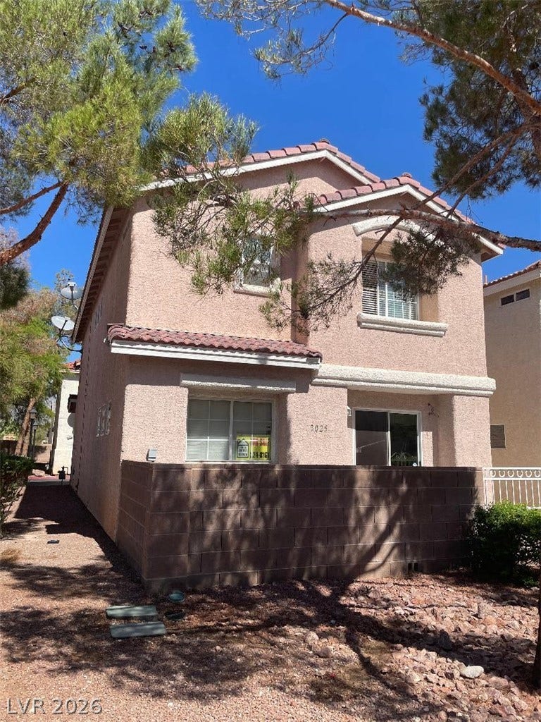 3025 Sunrise Bay Avenue, North Las Vegas, NV 89031 Mature trees shade a classic stucco exterior with architectural tile roofing and private patio space.