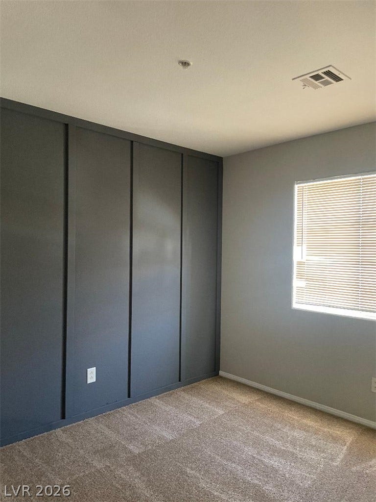 3025 Sunrise Bay Avenue, North Las Vegas, NV 89031 Board and batten detailing elevates this cozy bedroom featuring soft carpeting.
