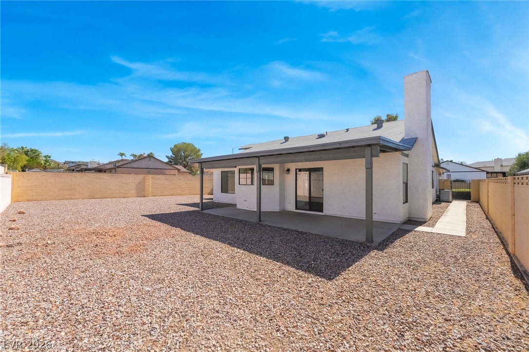 838 Anchor Drive, Henderson, NV 89015 An expansive gravel backyard features a covered concrete patio under clear desert skies.