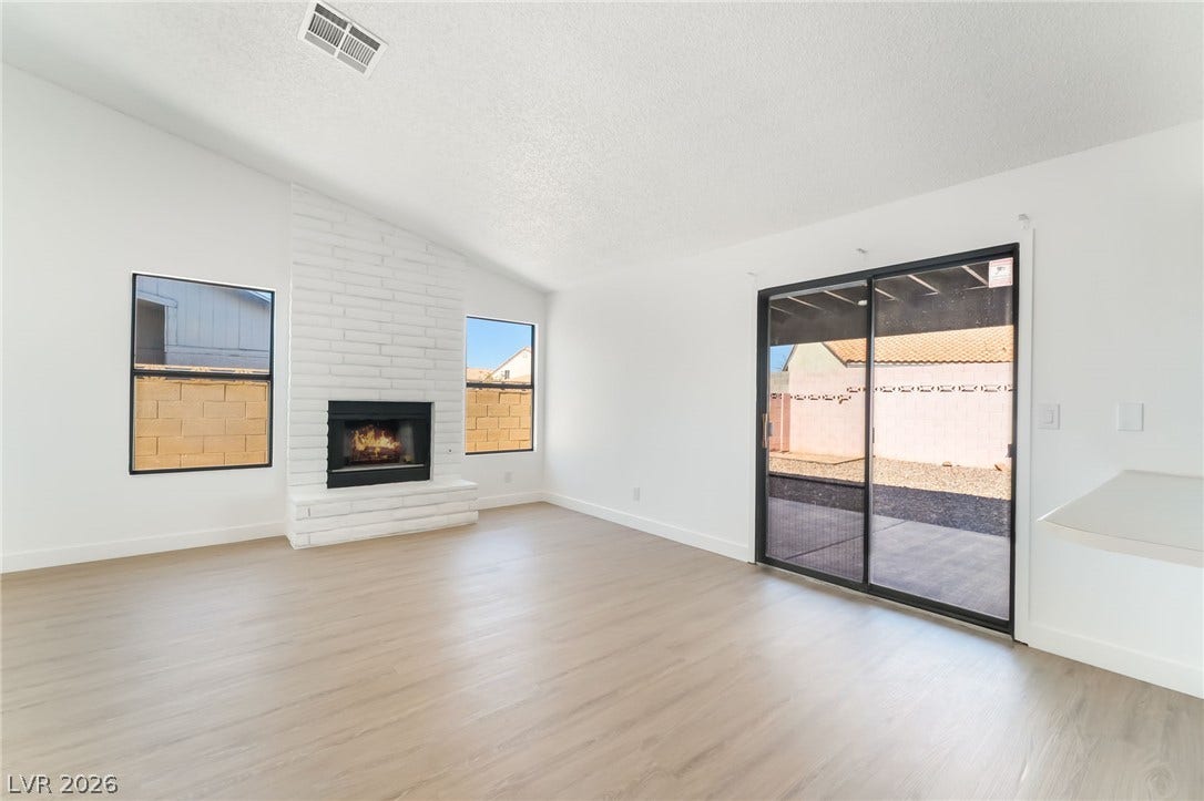 838 Anchor Drive, Henderson, NV 89015 A painted brick fireplace and wood-look flooring anchors this vaulted living area with patio access.