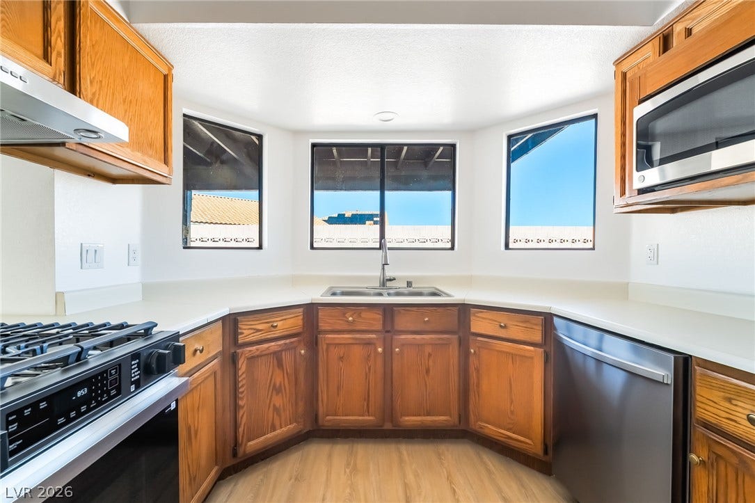 838 Anchor Drive, Henderson, NV 89015 Natural wood cabinetry frames a corner sink beneath wide windows framing blue skies.