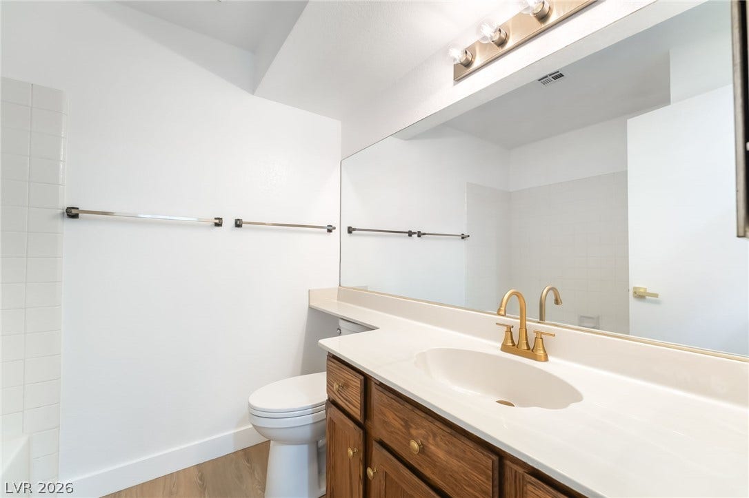 838 Anchor Drive, Henderson, NV 89015 A clean vanity area features warm wood cabinetry alongside a expansive wall mirror.