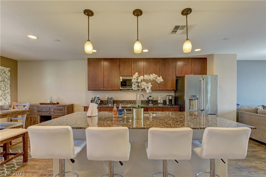 4650 Ranch House Road, #14, North Las Vegas, NV 89031 Rich wood cabinetry and expansive granite countertops define this modern, open-concept cooking space.