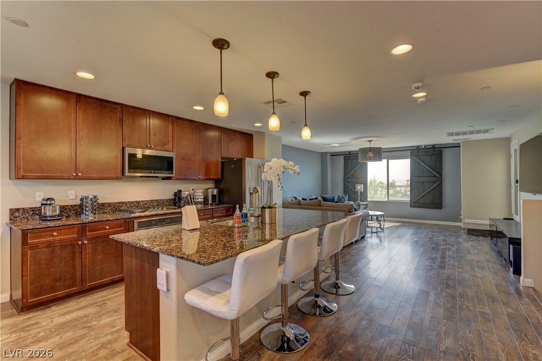4650 Ranch House Road, #14, North Las Vegas, NV 89031 Rich wood cabinetry and polished granite counters anchor this modern, open-concept kitchen.