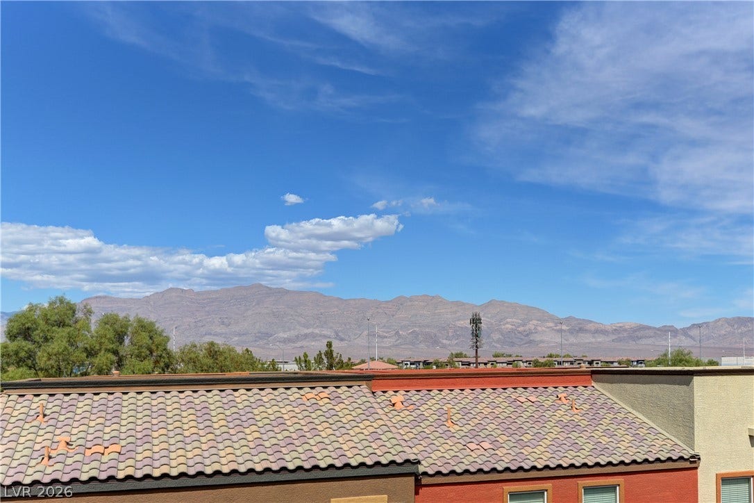 4650 Ranch House Road, #14, North Las Vegas, NV 89031 Distant mountain ranges rise behind neighboring tiled rooftops under a clear blue sky.