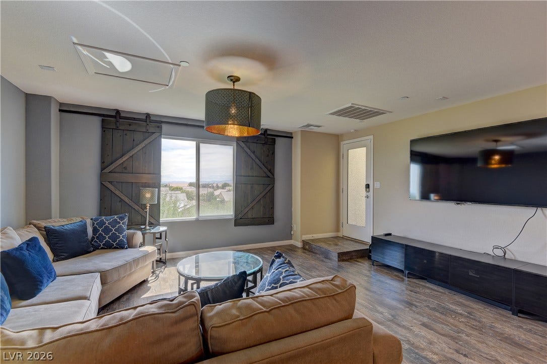 4650 Ranch House Road, #14, North Las Vegas, NV 89031 A spacious living area features wide windows alongside sliding barn-style shutters and wood-look flooring.