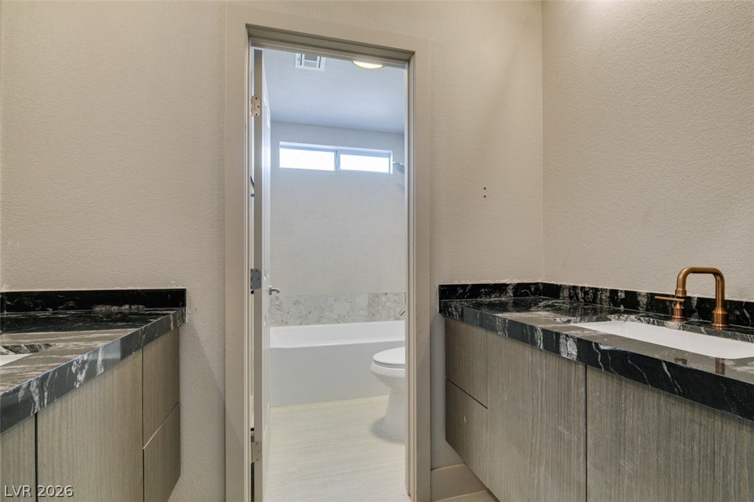 2897 Sunlit Glade Avenue, Henderson, NV 89074 Granite counters and custom cabinetry highlight this functional bathroom layout with an adjoining tub room.