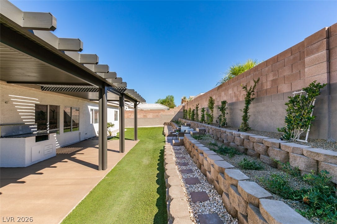 2897 Sunlit Glade Avenue, Henderson, NV 89074 A spacious covered patio overlooks a beautifully terraced lawn and neat stone garden beds.
