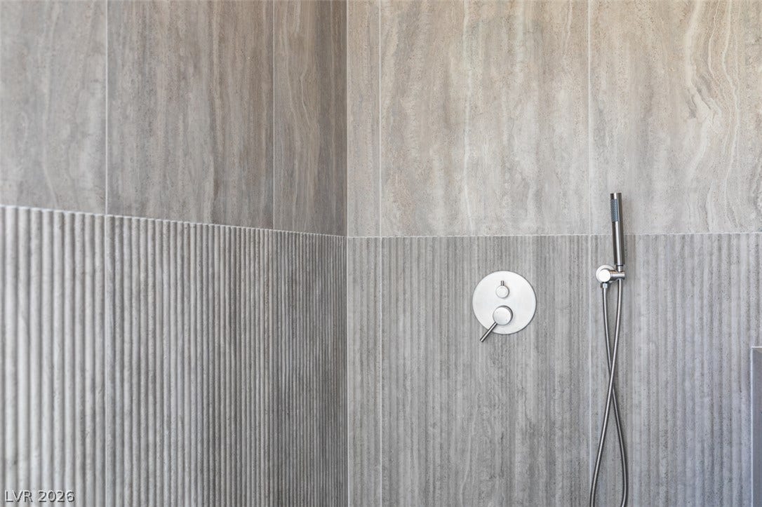 2897 Sunlit Glade Avenue, Henderson, NV 89074 Elegant textured tiling pairs with modern fixtures to elevate this walk-in shower design.