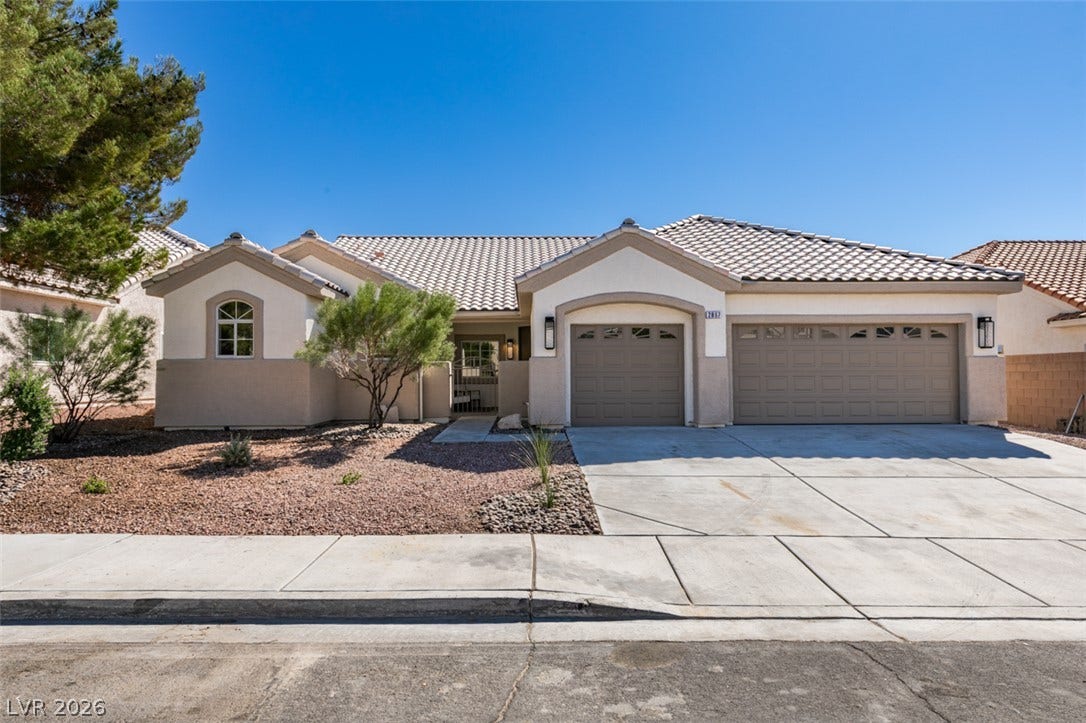 2897 Sunlit Glade Avenue, Henderson, NV 89074 Spanish tile roofing and desert-style landscaping enhance the curb appeal of this stucco exterior.