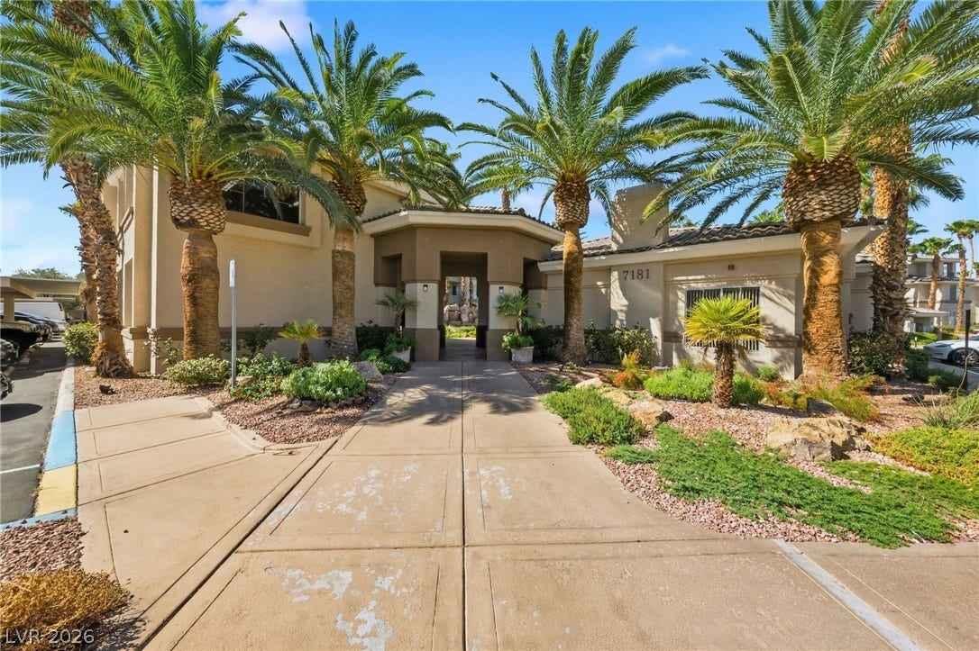 7139 S Durango Drive, #110, Las Vegas, NV 89113 Towering palm trees flank the wide paved walkway leading to the covered main entrance.