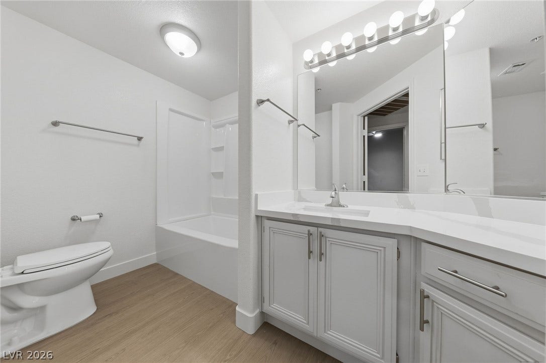 7139 S Durango Drive, #110, Las Vegas, NV 89113 Bright vanity lighting illuminates this modern bathroom complete with stone counters and wood-look flooring.