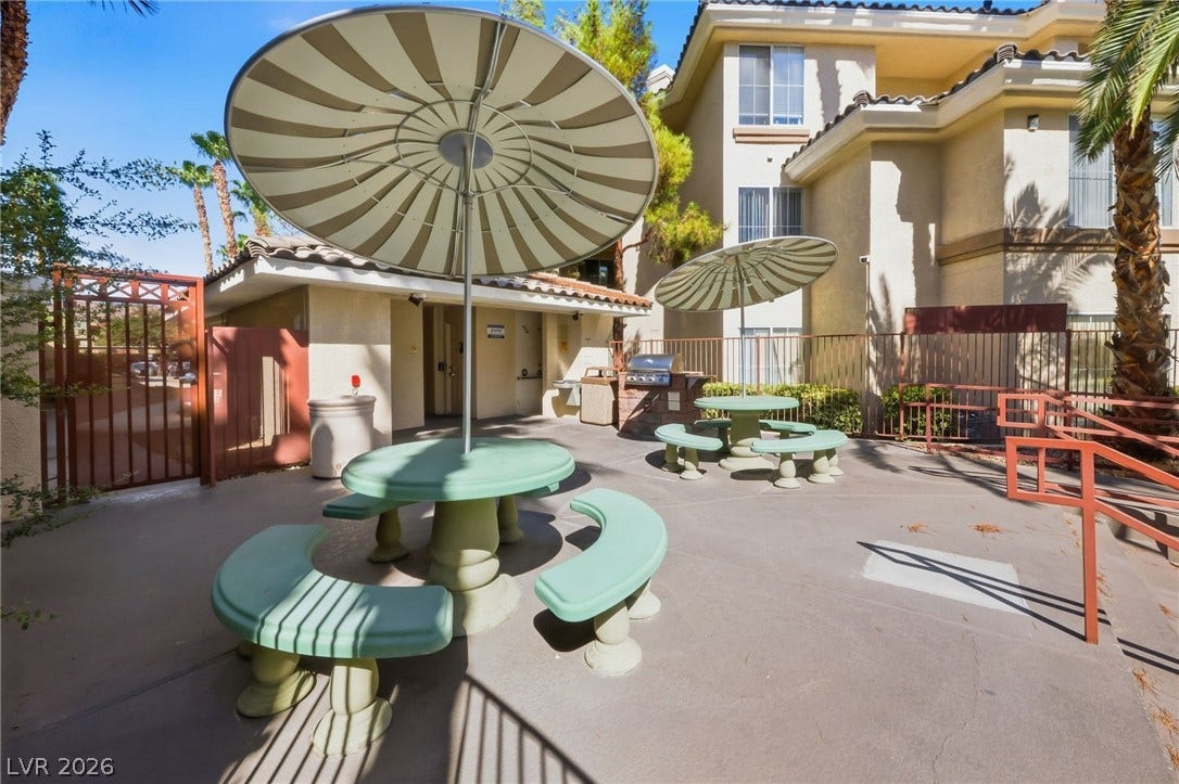 7139 S Durango Drive, #110, Las Vegas, NV 89113 An inviting outdoor common area features built-in barbecue stations and concrete picnic tables with shade umbrellas.