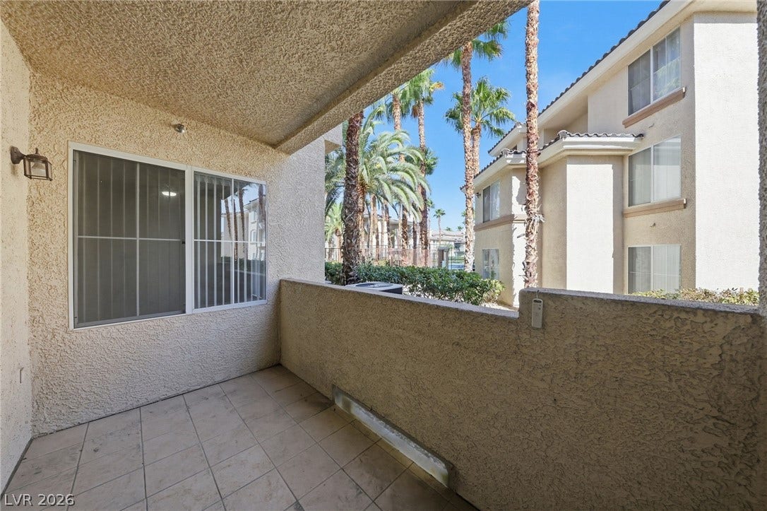 7139 S Durango Drive, #110, Las Vegas, NV 89113 A private covered balcony features tiled flooring and overlooks palm trees.