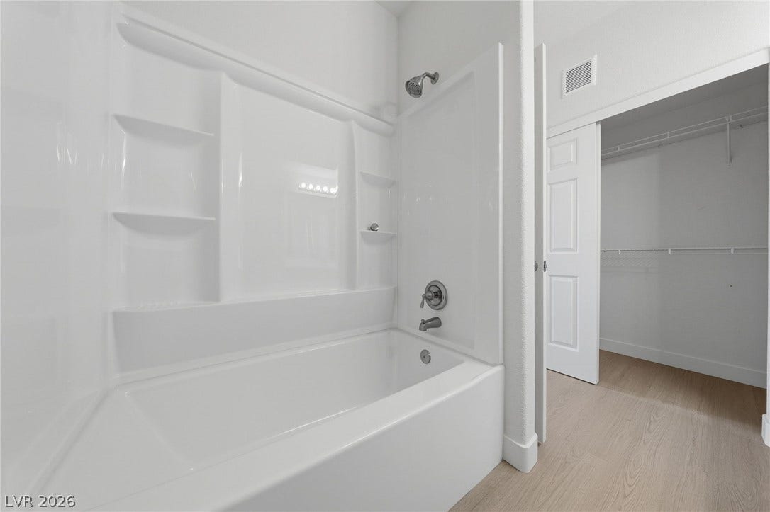 7139 S Durango Drive, #110, Las Vegas, NV 89113 An inviting soaking tub pairs with wood-style flooring adjacent to a spacious walk-in closet.