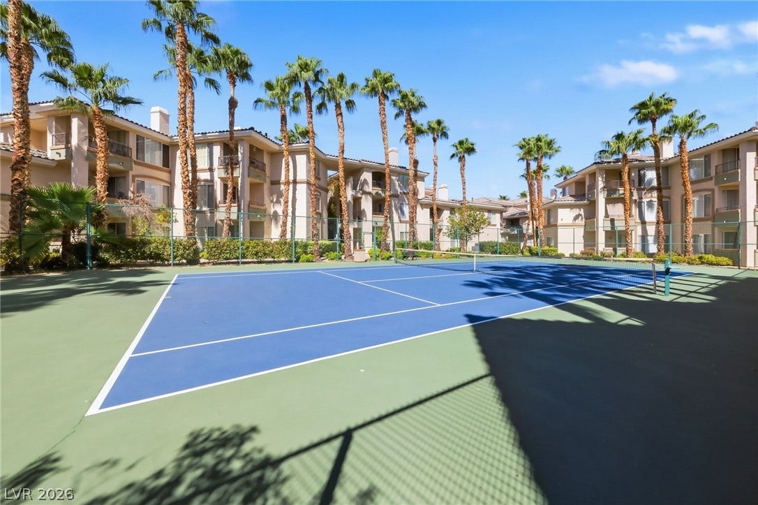 7139 S Durango Drive, #110, Las Vegas, NV 89113 Lush palm trees frame a pristine outdoor tennis court nestled within the residential community.