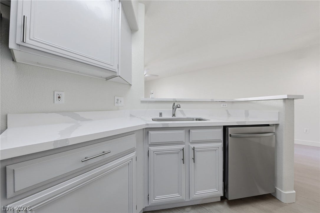 7139 S Durango Drive, #110, Las Vegas, NV 89113 Smooth stone countertops and white cabinetry define this sleek, open kitchen workspace.