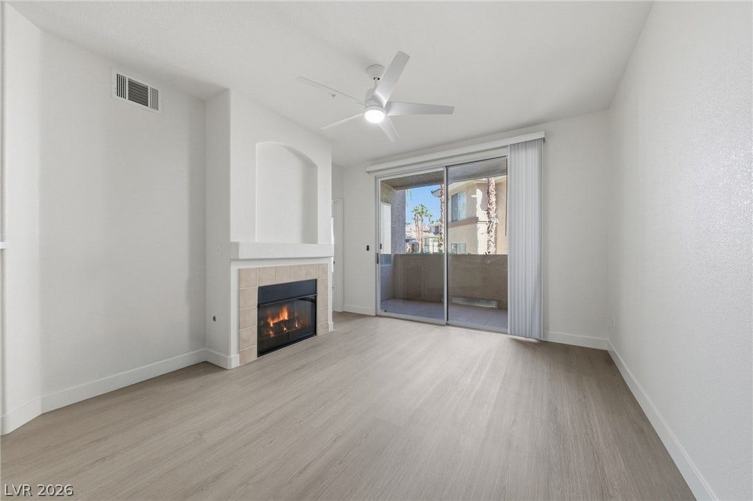 7139 S Durango Drive, #110, Las Vegas, NV 89113 Sliding glass doors open to a private balcony from this living space with a fireplace.