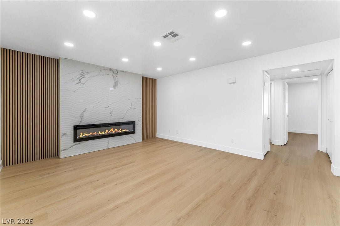 1017 Falconhead Lane, #102, Las Vegas, NV 89128 An elegant contemporary fireplace highlights this light-filled living area featuring smooth wood floors.