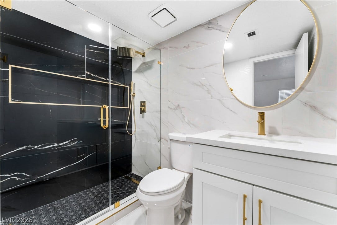 1017 Falconhead Lane, #102, Las Vegas, NV 89128 Elegant gold hardware accents contrast beautifully with the polished marble tile walls and glass shower.