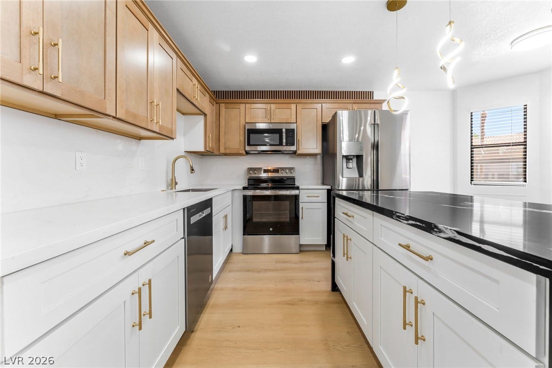 1017 Falconhead Lane, #102, Las Vegas, NV 89128 Modern cabinetry and stone countertops elevate this bright culinary space with dual-tone finishes.
