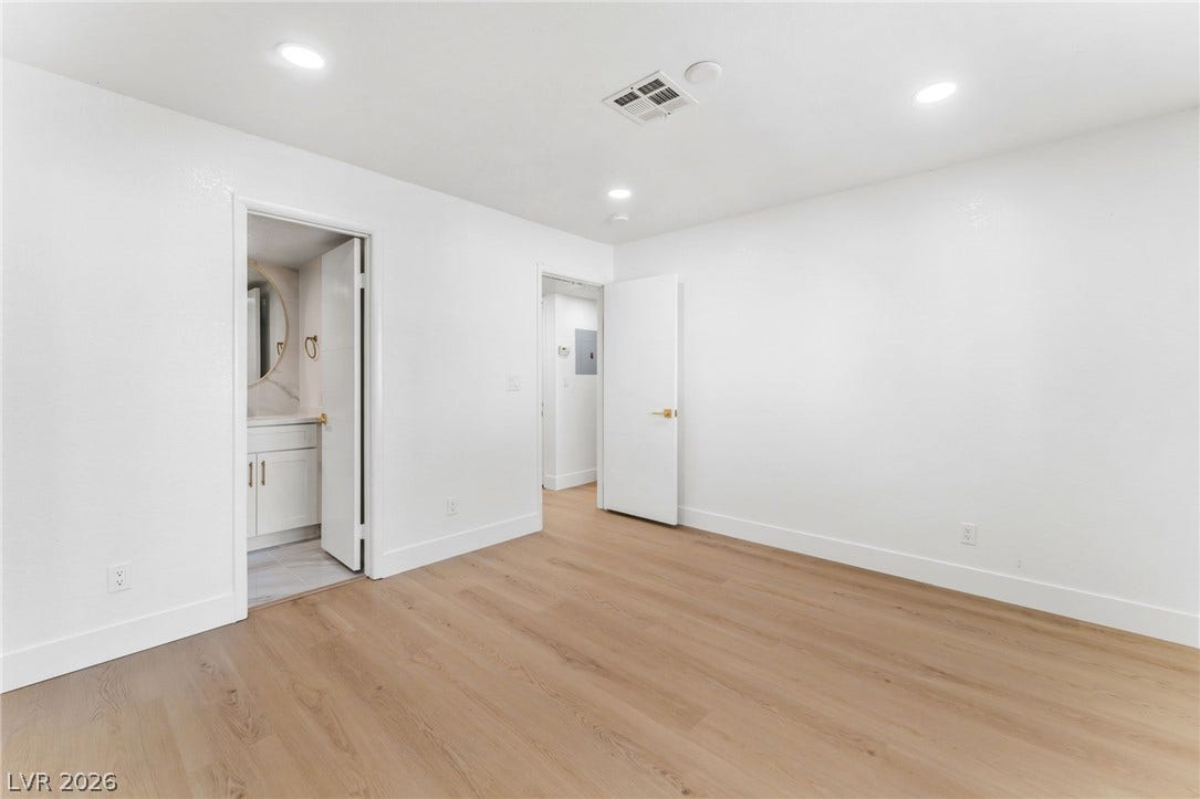 1017 Falconhead Lane, #102, Las Vegas, NV 89128 Gleaming wood floors anchor this clean, minimalist bedroom featuring recessed lighting and adjacent bath.