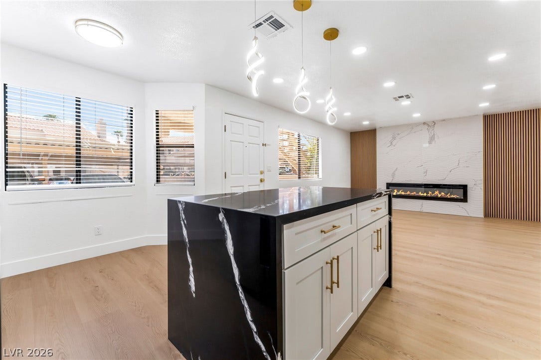 1017 Falconhead Lane, #102, Las Vegas, NV 89128 Smooth wood floors flow seamlessly past a modern stone fireplace and a sleek kitchen island.