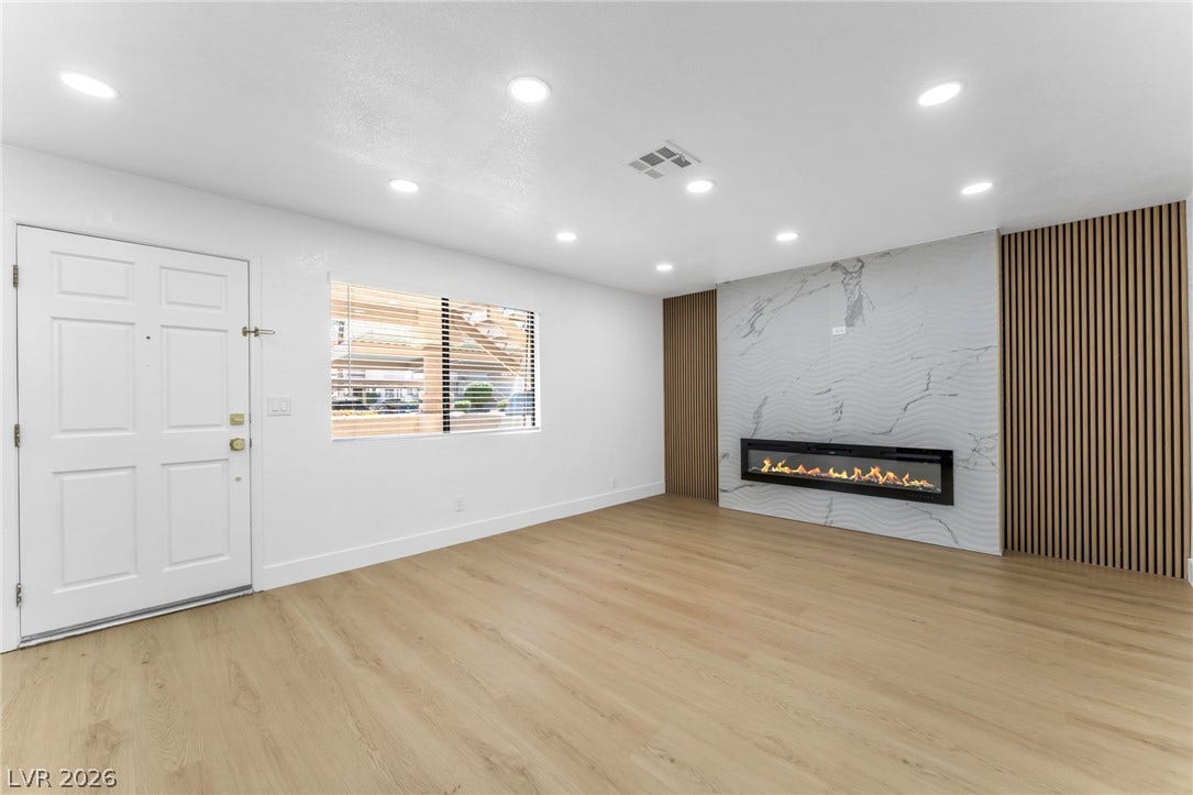 1017 Falconhead Lane, #102, Las Vegas, NV 89128 An elegant modern fireplace wall commands attention across the light-filled, open living space.