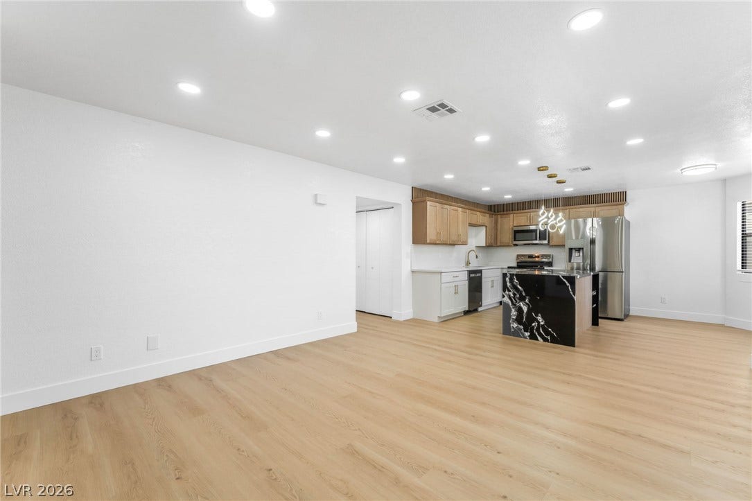1017 Falconhead Lane, #102, Las Vegas, NV 89128 Gleaming wood-look floors unite this expansive open kitchen and living area.