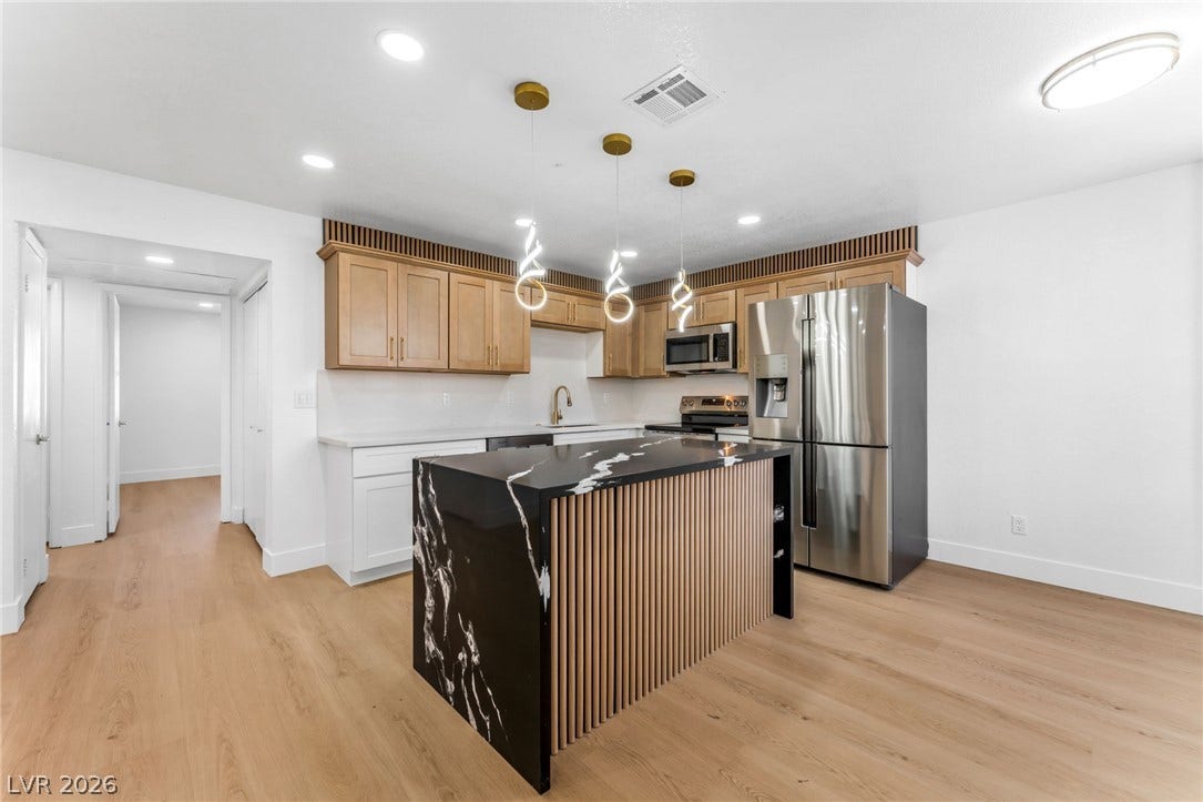 1017 Falconhead Lane, #102, Las Vegas, NV 89128 Modern finishes define this culinary space featuring a dark stone island and light wood flooring.