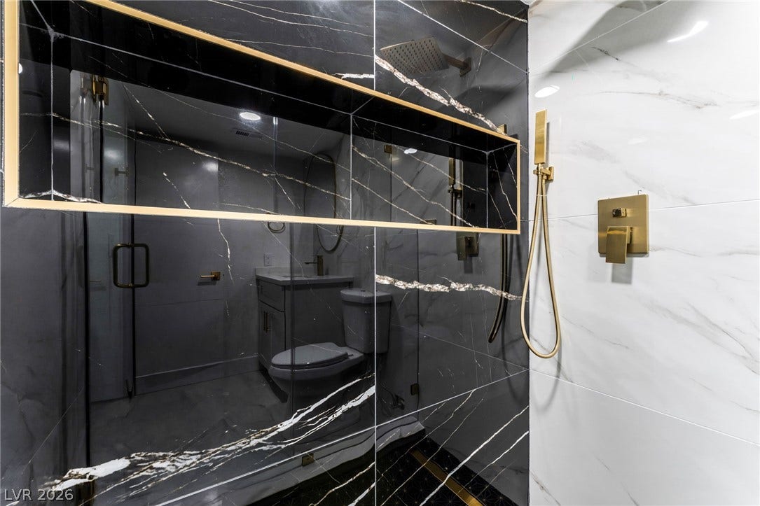 1017 Falconhead Lane, #102, Las Vegas, NV 89128 Striking marble-patterned tiles and gold hardware define this modern walk-in shower.