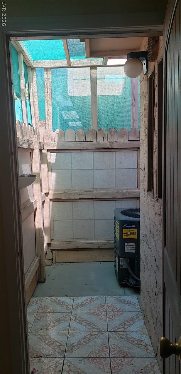 An enclosed utility porch area features ceramic tile flooring and wood wall construction.
