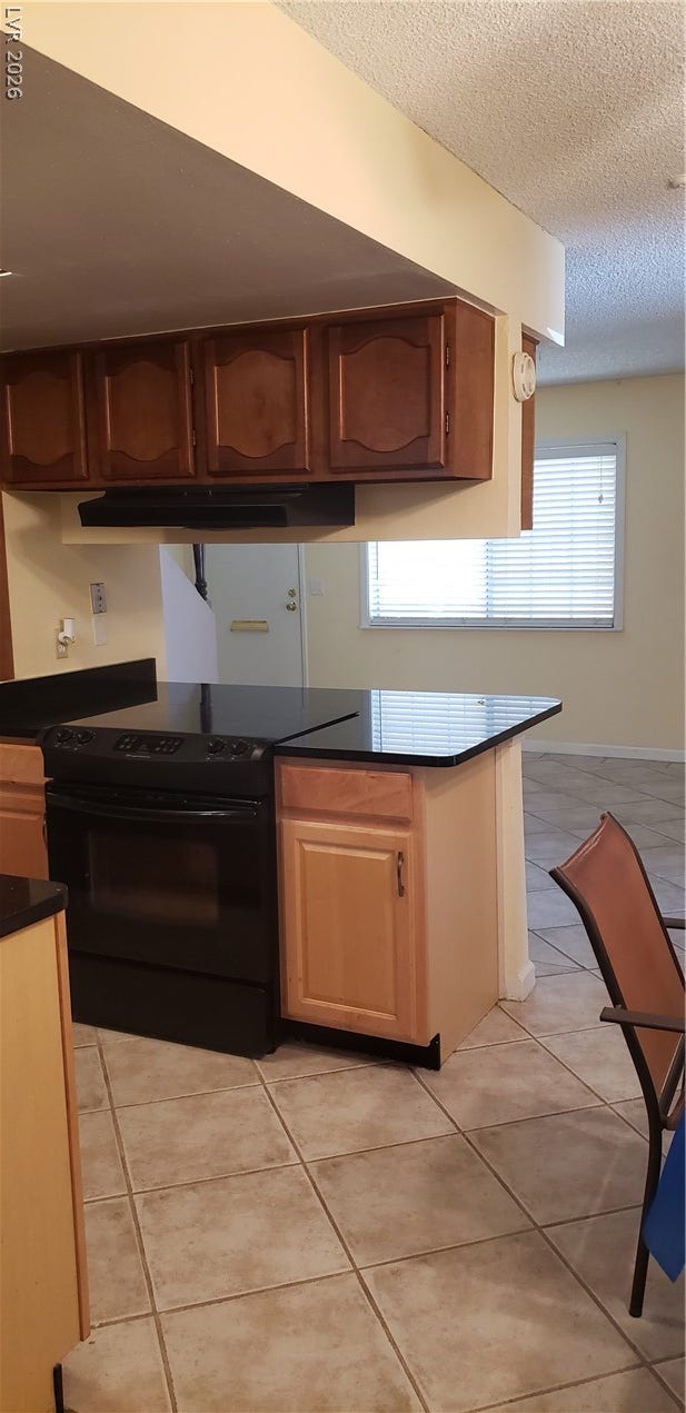 Tiled flooring and dark solid-surface countertops anchor this functional kitchen layout.