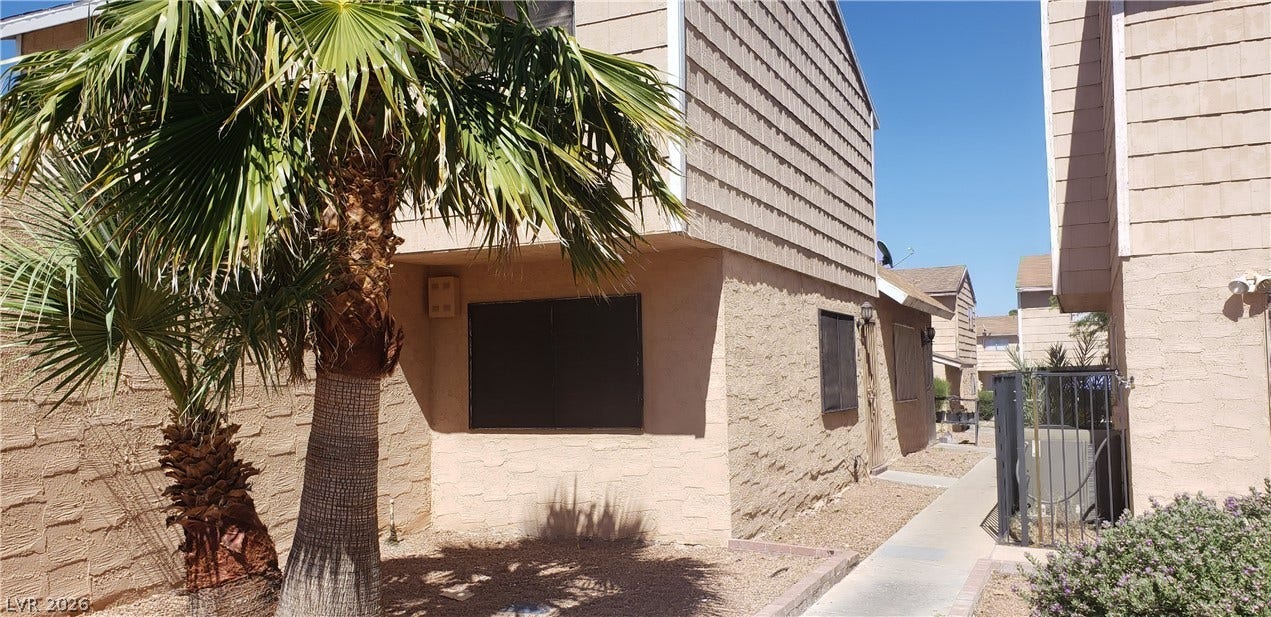 Mature palms frame this exterior clad in a mix of textured stucco and siding.