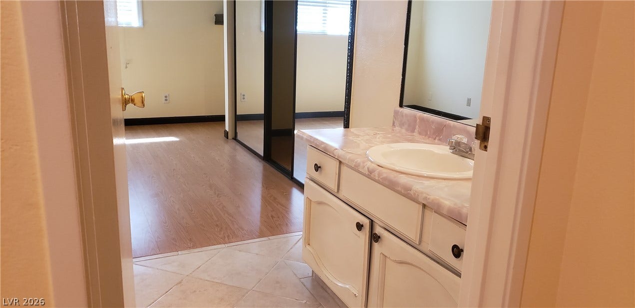 A well-appointed vanity area transitions smoothly into a adjacent room with wood flooring.