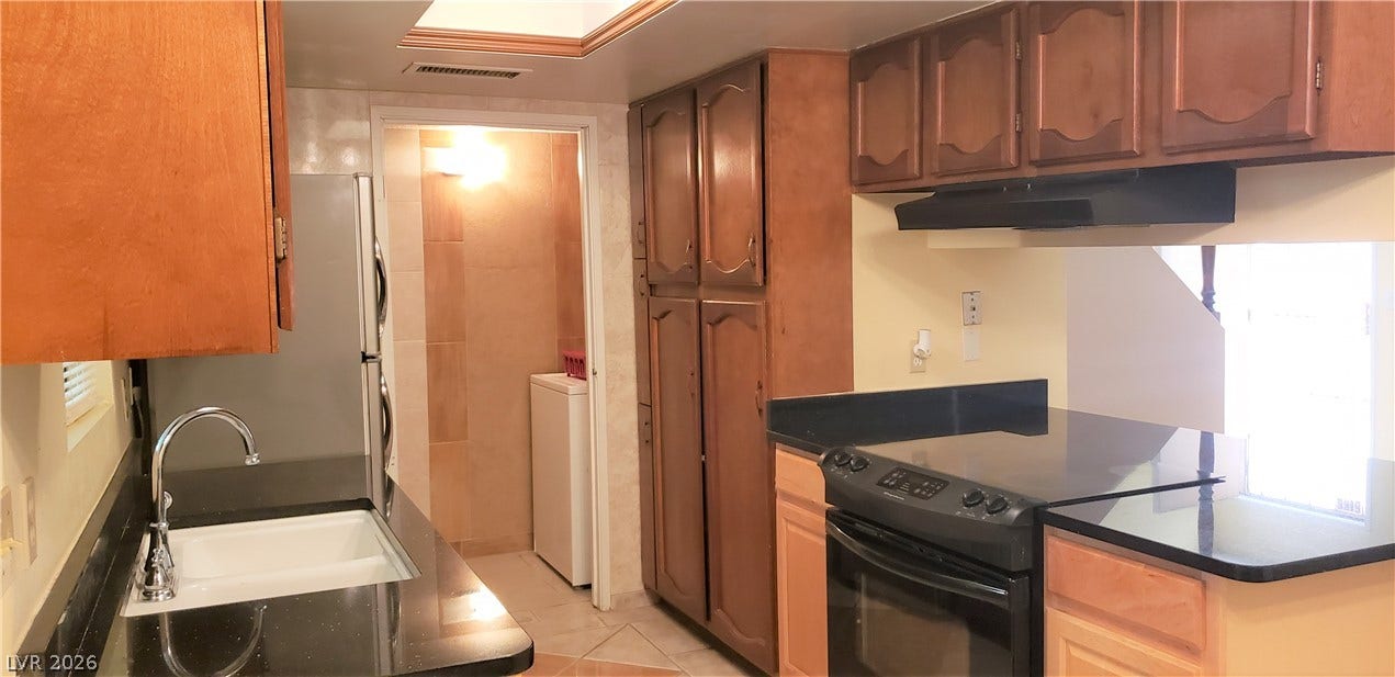Rich wood cabinetry paired with dark countertops defines this functional kitchen layout.