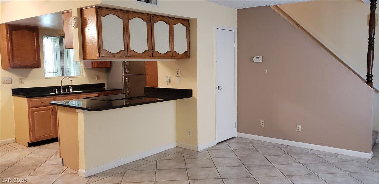 An open floor plan connects the tiled living space with a functional kitchen breakfast bar.