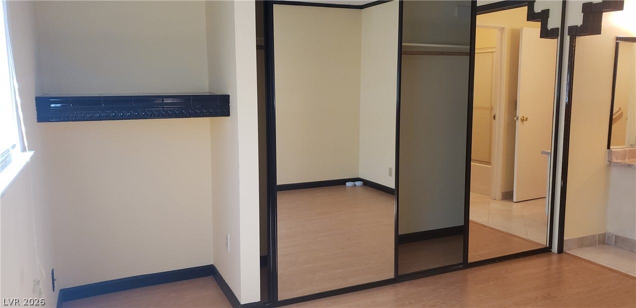 Sliding mirrored closet doors complement the wood flooring in this bright bedroom space.
